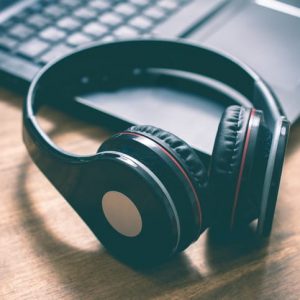 Black Wireless Overhead Headphones Lying On The Corner Of A Laptop Keyboard In An Office Custom-Made Personalized Hypnosis Recording